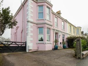 een roze en geel huis met een hek bij Melvill House in Falmouth
