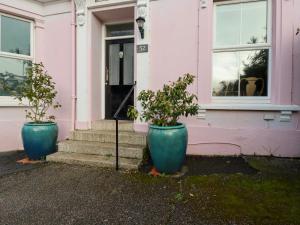 two large blue pots sitting outside of a pink house at Melvill House in Falmouth