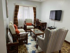 a living room with a couch and chairs and a television at A&L SUITES Lantana Road in Nairobi