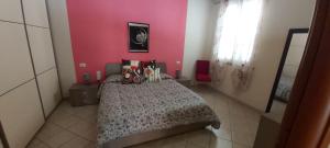 een slaapkamer met een bed en een roze muur bij SWEET HOME- AMPIO BIVANO A 10 MINUTI DALLE SPIAGGE in Quartu SantʼElena