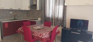 uma cozinha com uma mesa com cadeiras vermelhas e uma televisão em SWEET HOME- AMPIO BIVANO A 10 MINUTI DALLE SPIAGGE em Quartu SantʼElena