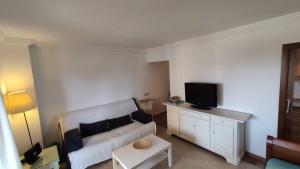 イスラ・カネラにあるApartamento Los Pelícanosの白いソファとテレビのあるリビングルーム