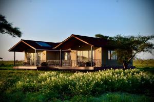 una casa en un campo con flores delante en Serengeti Sametu Camp, en Parque Nacional del Serengeti