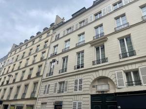 Un grand bâtiment blanc avec de nombreuses fenêtres donne sur une rue. dans l'établissement Bohemian Flat - Lovely Marais, à Paris