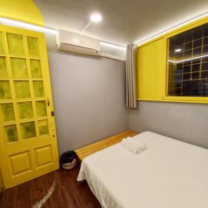 a room with a bed and a window and a yellow door at Hanowood Homestay in Hanoi