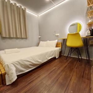 a bedroom with a bed and a yellow chair at Hanowood Homestay in Hanoi