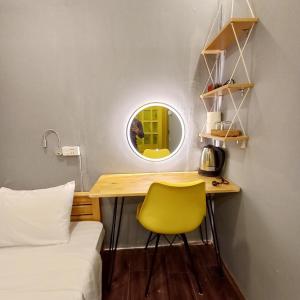 Habitación pequeña con escritorio y silla amarilla. en Hanowood Homestay en Hanoi