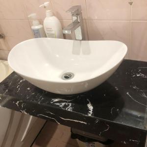 a white sink on a black counter in a bathroom at Hanowood Homestay in Hanoi