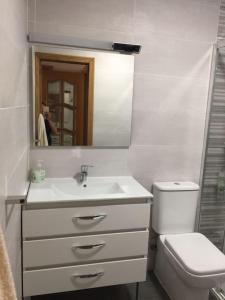 een badkamer met een wastafel, een toilet en een spiegel bij Two Bed in the Manga in La Manga del Mar Menor