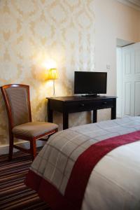 a bedroom with a bed and a desk with a television at Eskdale Hotel in Langholm
