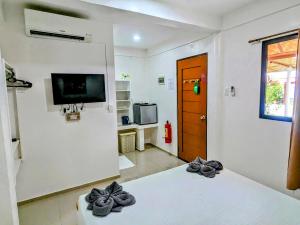 Zimmer mit einem Bett, einem TV und einer Tür in der Unterkunft Astillo's Guest Houses in Moalboal