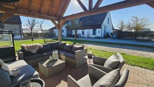 a patio with couches and chairs and a house at Boutique B&B Droomkerke in Ruiselede