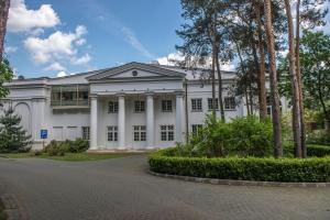 a white building with trees in front of it at Klub Sosnowy in Warsaw