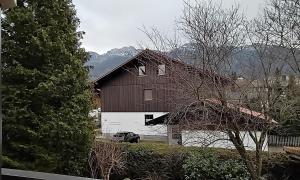 um celeiro castanho e branco com uma garagem branca em ciao-aschau FeWo Volkmann em Aschau