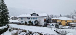 a white house with blue windows in a snow covered yard at ciao-aschau FeWo Schöne-Aussicht in Aschau