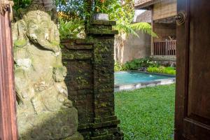 una statua in pietra accanto a un cortile con piscina di Tano Home Villas ad Ubud