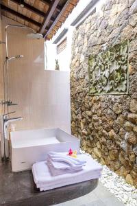 e bagno con vasca e parete in pietra. di Tano Home Villas ad Ubud