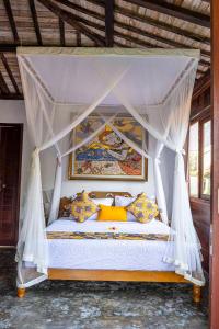 una camera con letto a baldacchino e cuscini gialli di Tano Home Villas ad Ubud