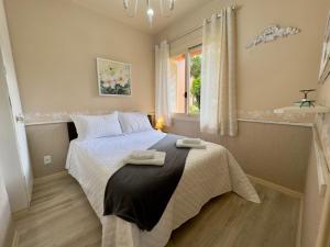 een slaapkamer met een bed met twee handdoeken erop bij Apartamento c/LAREIRA CONDOMÍNIO, próx LAGO NEGRO in Gramado