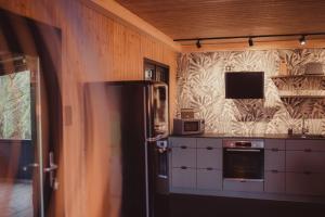 Ô NaNo Glamping في Dalhem: مطبخ مع ثلاجة وتلفزيون على الحائط