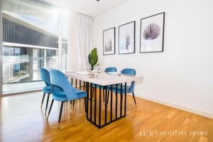 a dining room with a white table and blue chairs at LUX - The Bluewater Island Suite in Dubai