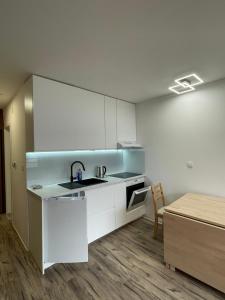 - une cuisine avec des placards blancs, un évier et une table dans l'établissement Studio Pod Kaninom, à Bovec