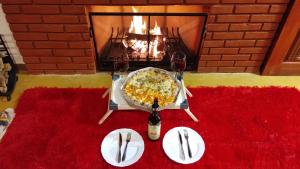 a table with a pizza and a fire place at Chales Sabor Dos Ventos in Gonçalves