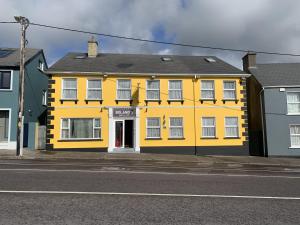 um edifício amarelo no lado de uma rua em Boland's Accommodation Dingle em Dingle