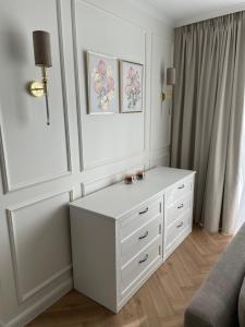 biała sypialnia z komodą i lustrem w obiekcie Klif Apartamenty Nadmorskie Tarasy w Kołobrzegu +37 zdjęć