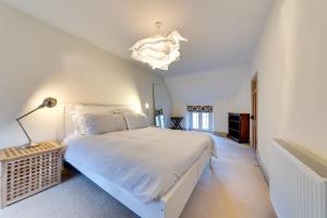 a bedroom with a large white bed and a chandelier at Music School Cottage 1 in Oundle