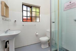 a bathroom with a toilet and a sink and a window at Teak Place Guest Rooms in Krugersdorp