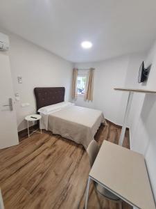 Habitación pequeña con cama y mesa en Hostal Santa Ana, en Huelva