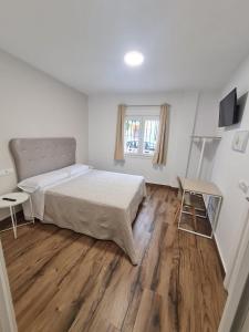 Dormitorio blanco con cama y mesa en Hostal Santa Ana, en Huelva