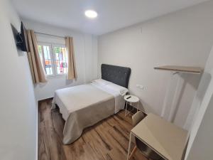 Habitación pequeña con cama y ventana en Hostal Santa Ana, en Huelva