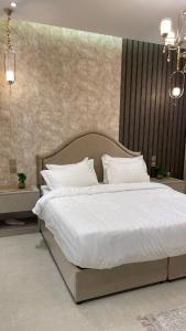 a bedroom with a large bed with white sheets and pillows at برج داماك الجوهرة جدة - Damac al jawharah tower in Jeddah