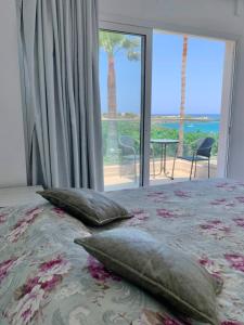 een slaapkamer met een bed met kussens en een groot raam bij Saradari Beach Hotel - Adults Only in Chersonissos