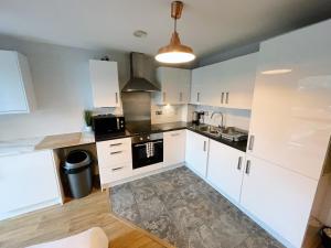 a kitchen with white cabinets and a sink and a stove at Newcastle River View Quayside Apartment - Private Parking - Sleeps 7 - City Centre Walking Distance in Gateshead