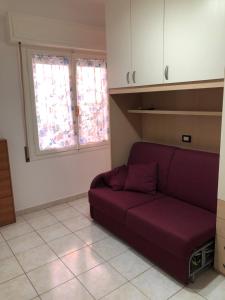 sala de estar con sofá púrpura y 2 ventanas en La Casa della Nini, en San Remo