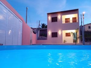 a villa with a swimming pool in front of a house at Duplex de 2 quartos com ar condicionado , piscina e estacionamento in Aracati