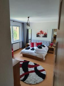 a bedroom with a bed with red pillows and a rug at Dom Gościnny Marta in Krynica Morska