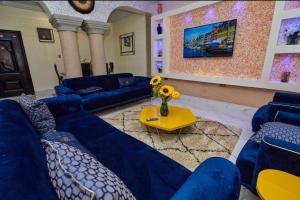 ein Wohnzimmer mit blauen Sofas und einem gelben Tisch in der Unterkunft Pomaa Villa in Kumasi