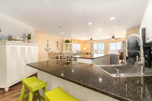 Spacious Penthouse Ocean Front 7 BR Condo - Ambassador Villas Unit 401 في ميرتل بيتش: مطبخ مع حوض وكاونتر مع كراسي