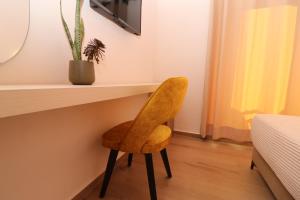 una silla amarilla sentada bajo un escritorio en una habitación en Fegi Rooms en Himare