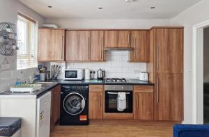 eine Küche mit Holzschränken, einer Waschmaschine und einem Trockner in der Unterkunft Albert Duplex Apartment in Hendon NW4 in Hendon