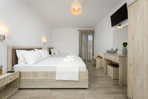 a bedroom with a large white bed and a flat screen tv at Aspa's House in Limenas