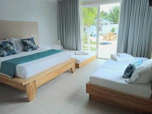 two beds in a bedroom with a view of a patio at Oasis Tolú Hotel Boutique in Tolú