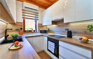 a kitchen with white cabinets and a wooden counter top at Nice home in Sisak with Outdoor swimming pool, WiFi and Heated swimming pool in Sisak