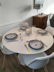 una mesa blanca con platos y vasos. en Seaview cosy 2 bed home in Lamlash, en Lamlash