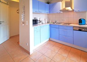 a kitchen with blue cabinets and a tile floor at Ferienwohnung Seestern (Ref. 128659u1) in Baabe