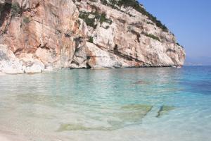 a beach with clear water and a rocky cliff at Hotel Ristorante La Conchiglia in Cala Gonone
